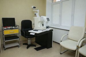 Ögonklinikrum med utrustning för synundersökning, svart stol och fönster.