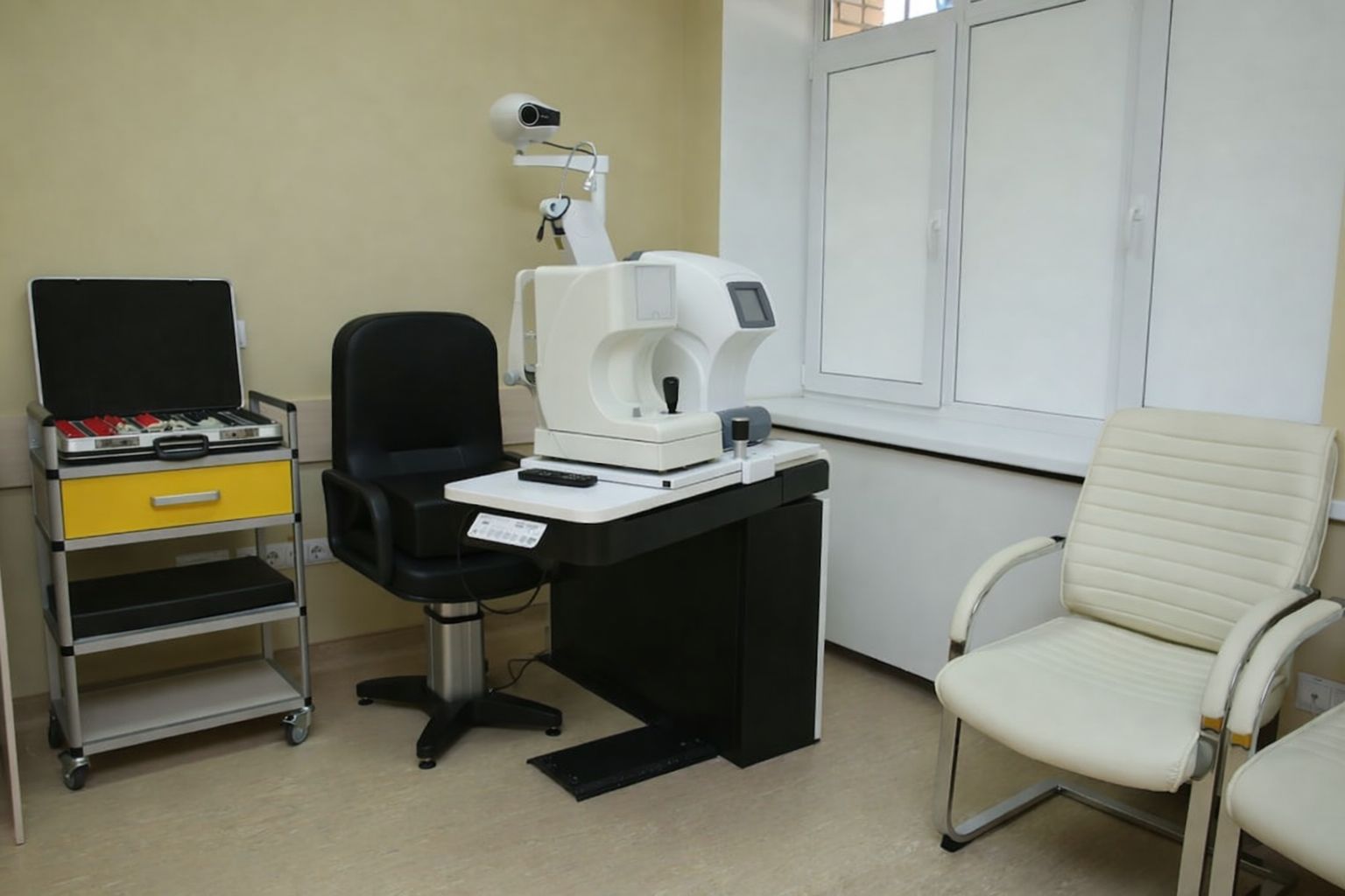Ögonklinikrum med utrustning för synundersökning, svart stol och fönster.